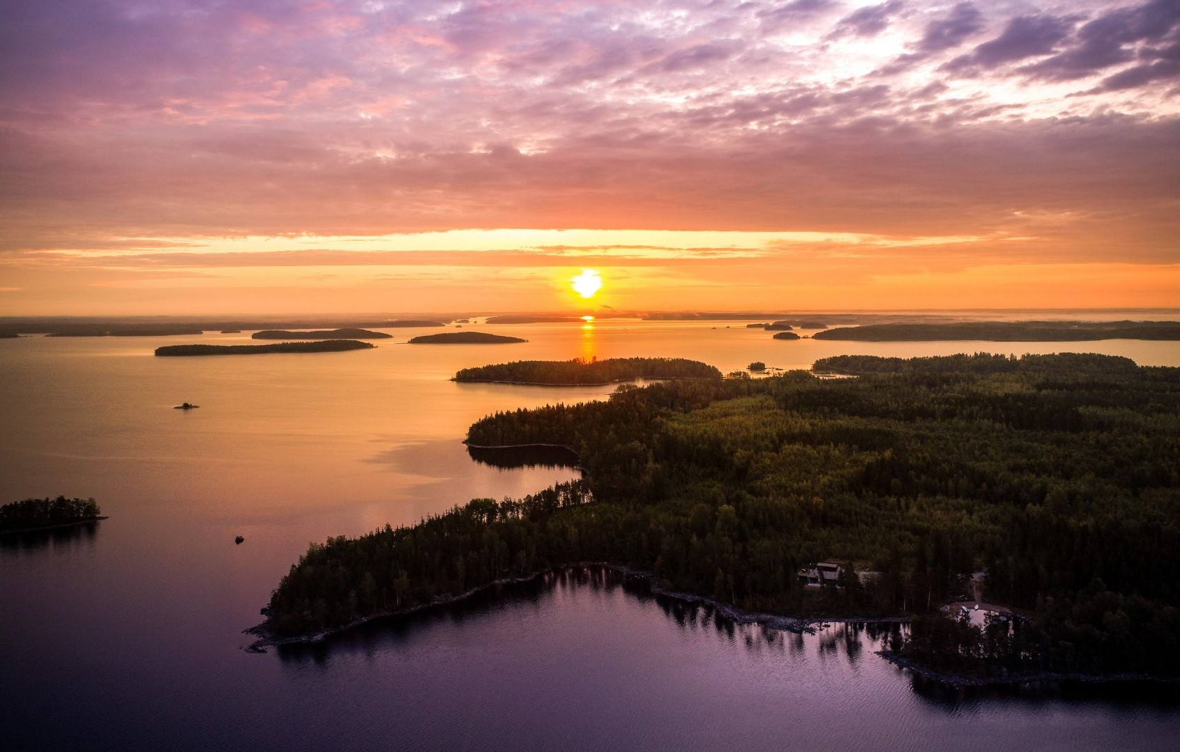 The archipelago of lake Saimaa. The sun is setting, and the lilac colors of the sky are reflected in the water.